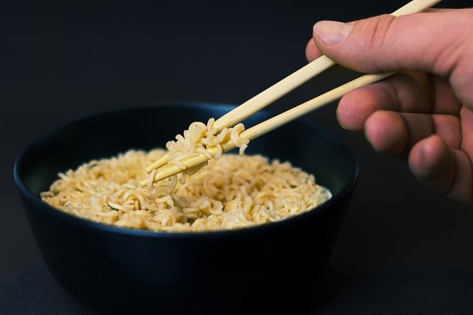 A bowl of noodles being lifted with chopsticks