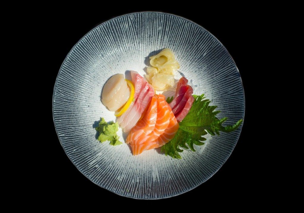 A sashimi plate lit against a dark background